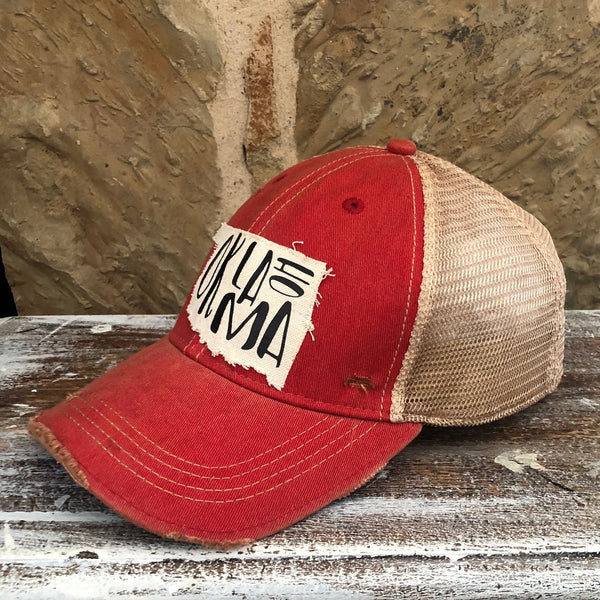 Right side view of the Oklahoma hat by BohoGroove with black Oklahoma lettering on a distressed off-white patch in the shape of the state of Oklahoma on a red vintage distressed snapback.