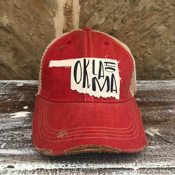 Oklahoma hat by BohoGroove with black Oklahoma lettering on a distressed off-white patch in the shape of the state of Oklahoma on a red vintage distressed snapback.