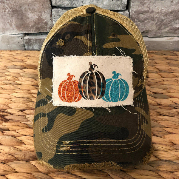 Pumpkin hat by BohoGroove featuring orange, leopard, and turquoise glitter pumpkin graphics on a cream patch on a camo vintage distressed snapback.