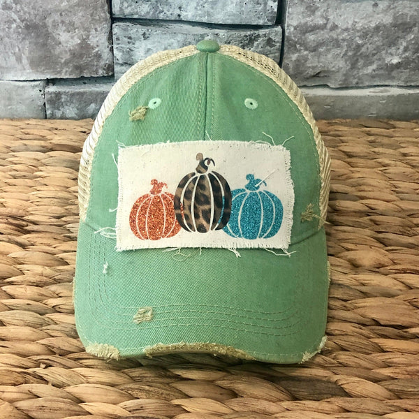 Pumpkin hat by BohoGroove featuring orange, leopard, and turquoise glitter pumpkin graphics on a cream patch on a mint vintage distressed snapback.