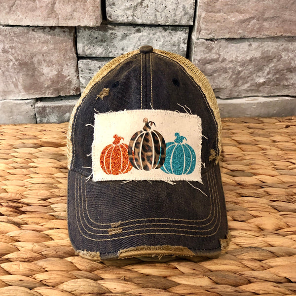 Pumpkin hat by BohoGroove featuring orange, leopard, and turquoise glitter pumpkin graphics on a cream patch on a navy blue vintage distressed snapback.