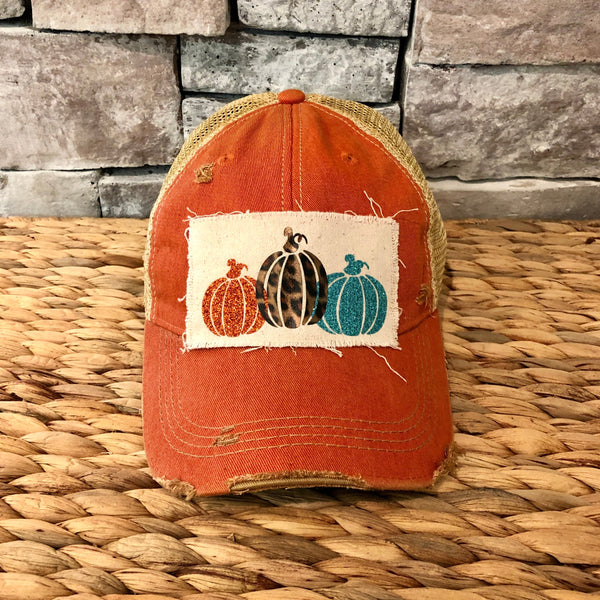 Pumpkin hat by BohoGroove featuring orange, leopard, and turquoise glitter pumpkin graphics on a cream patch on an orange vintage distressed snapback.