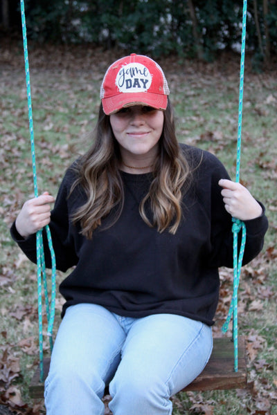Girl riding a swing wearing a red BohoGroove Game Day hat