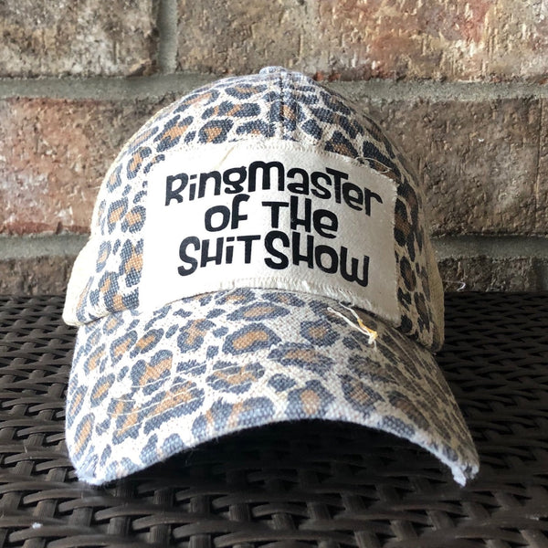 Ringmaster of the Shit Show hat by BohoGroove with black Ringmaster of the Shit Show lettering on a distressed off-white patch on a leopard vintage distressed snapback trucker hat.