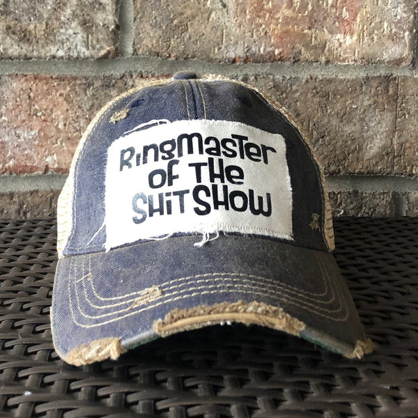Ringmaster of the Shit Show hat by BohoGroove with black Ringmaster of the Shit Show lettering on a distressed off-white patch on a navy blue vintage distressed snapback trucker hat.