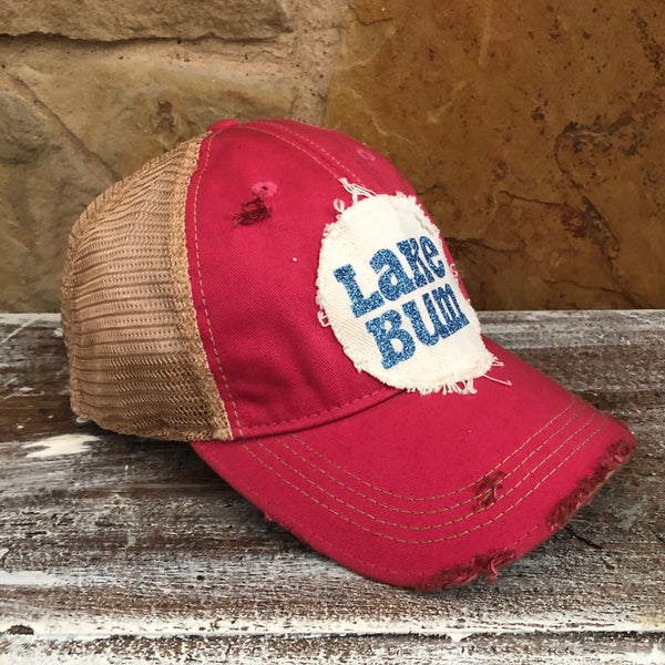 Lake Bum hat by BohoGroove with blue glitter Lake Bum lettering on distressed off-white patch on a pink vintage distressed snapback left side.