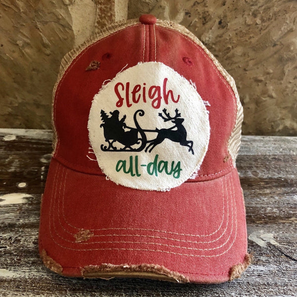 Sleigh All Day hat by BohoGroove with red and green lettering and a black Santa sleigh with reindeer graphic on a distressed off-white custom patch on a red vintage distressed snapback.