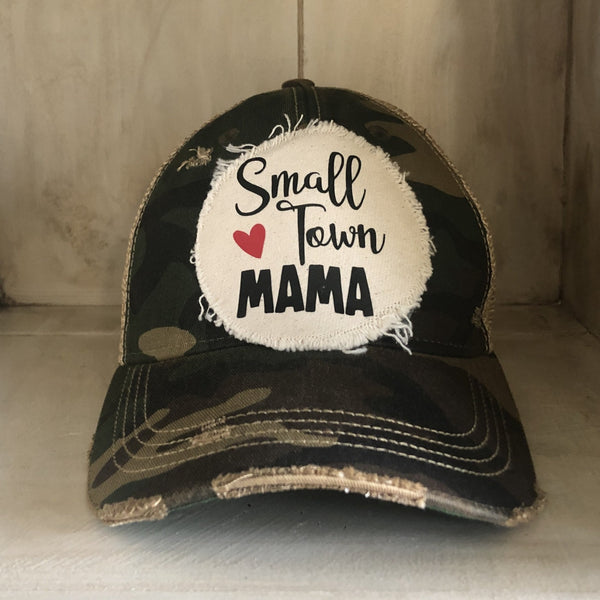Small Town Mama hat by BohoGroove with black Small Town Mama lettering and red heart graphic on a distressed off-white patch on a camo vintage distressed snapback.