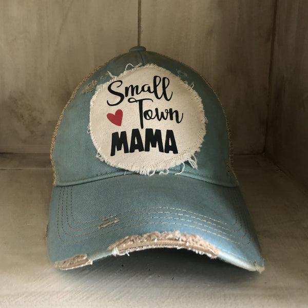 Small Town Mama hat by BohoGroove with black Small Town Mama lettering and red heart graphic on a distressed off-white patch on a light blue vintage distressed snapback.