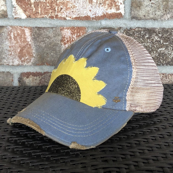 Sunflower hat by BohoGroove with yellow sunflower petals and a black glitter sunflower center on a light blue vintage distressed snapback right side.
