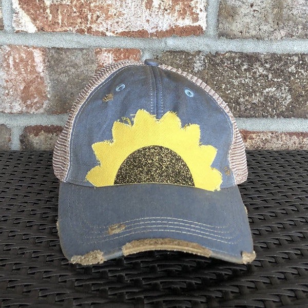 Sunflower hat by BohoGroove with yellow sunflower petals and a black glitter sunflower center on a light blue vintage distressed snapback.
