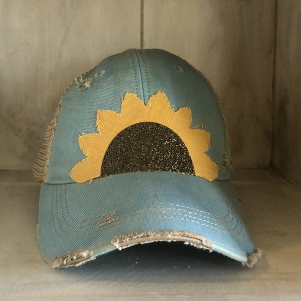 Sunflower hat by BohoGroove with yellow sunflower petals and a black glitter sunflower center on an ocean blue vintage distressed snapback.