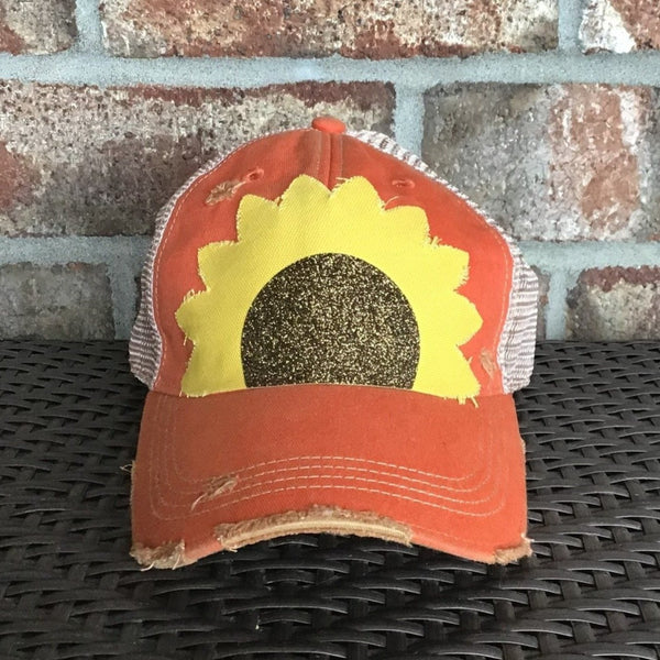 Sunflower hat by BohoGroove with yellow sunflower petals and a black glitter sunflower center on an orange vintage distressed snapback.