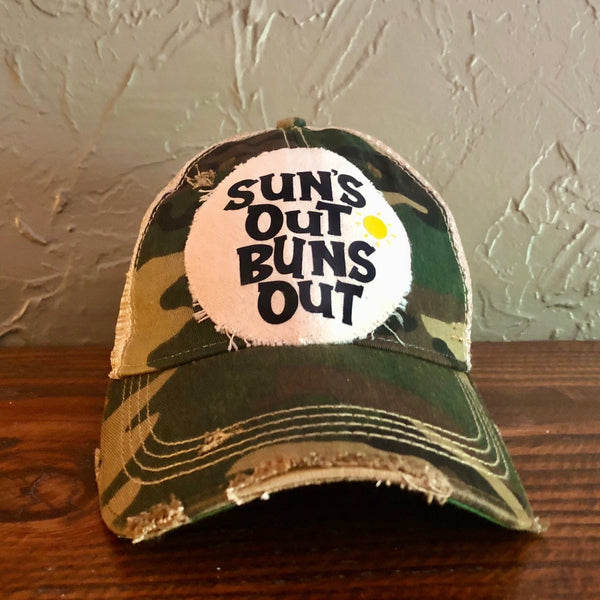 Suns Out Buns Out hat by BohoGroove with black lettering and yellow sun graphic on distressed off-white patch on camo vintage distressed snapback.