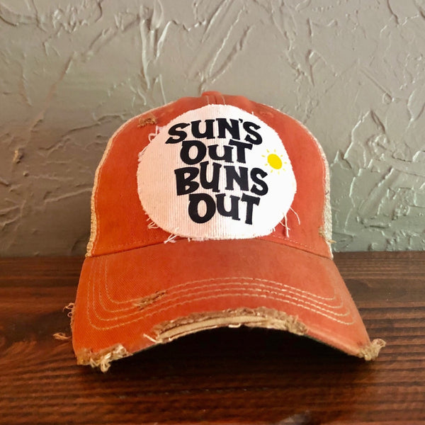 Suns Out Buns Out hat by BohoGroove with black lettering and yellow sun graphic on distressed off-white patch on orange vintage distressed snapback.