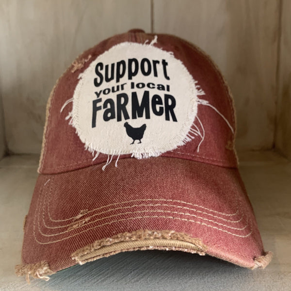 Support Your Local Farmer hat by BohoGroove with black Support Your Local Farmer lettering and chicken graphic on a distressed off-white patch on a brick red vintage distressed snapback.