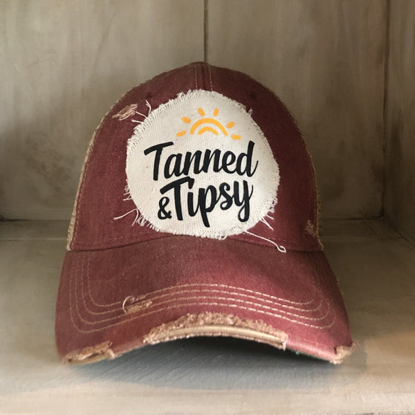 Tanned and Tipsy Hat by BohoGroove on a distressed brick red snapback trucker hat with hand-applied patch design and vintage weathered style.