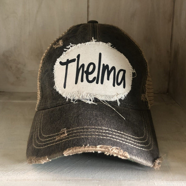 Thelma hat by BohoGroove with black Thelma lettering on a distressed off-white patch on a black vintage distressed snapback trucker hat.