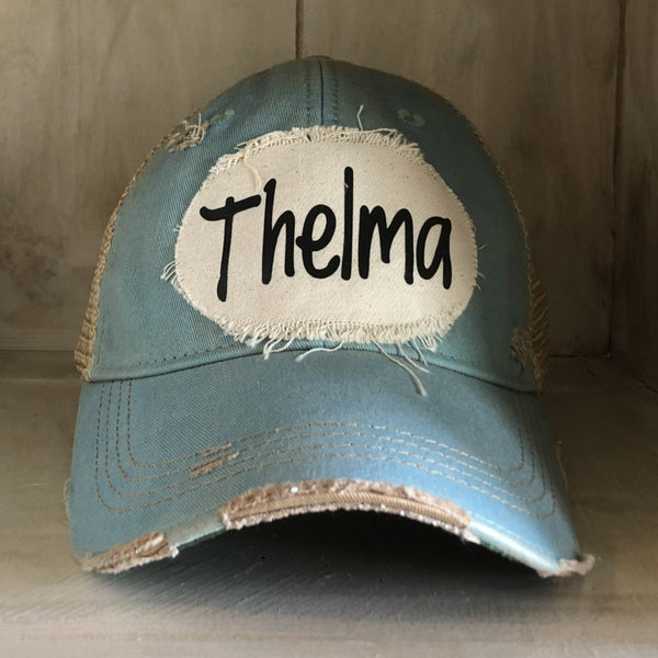 Thelma hat by BohoGroove with black Thelma lettering on a distressed off-white patch on a light blue vintage distressed snapback trucker hat.
