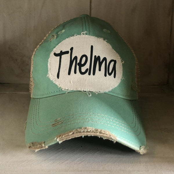 Thelma hat by BohoGroove with black Thelma lettering on a distressed off-white patch on a mint vintage distressed snapback trucker hat.