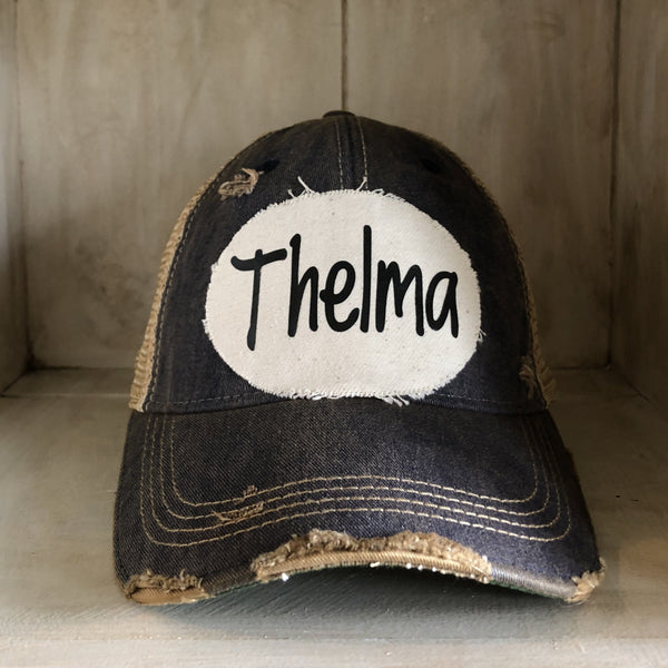 Thelma hat by BohoGroove with black Thelma lettering on a distressed off-white patch on a navy blue vintage distressed snapback trucker hat.