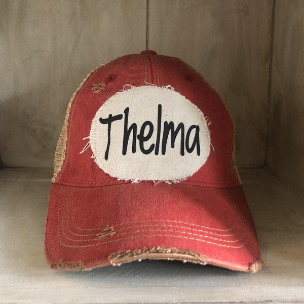 Thelma hat by BohoGroove with black Thelma lettering on a distressed off-white patch on a red vintage distressed snapback trucker hat.