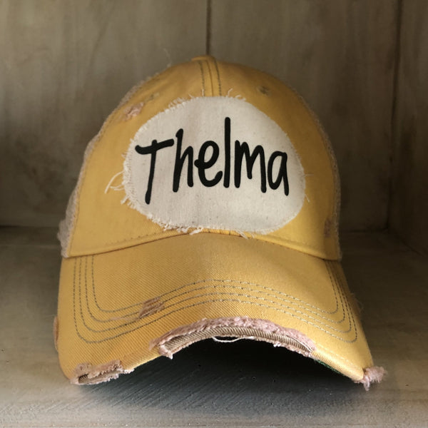 Thelma hat by BohoGroove with black Thelma lettering on a distressed off-white patch on a yellow vintage distressed snapback trucker hat.