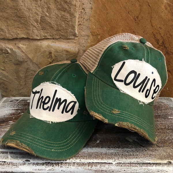 Matching Thelma and Louise hats by BohoGroove with black lettering on distressed off-white patches on vintage distressed snapback hats, displayed together as friendship hats inspired by Thelma and Louise.