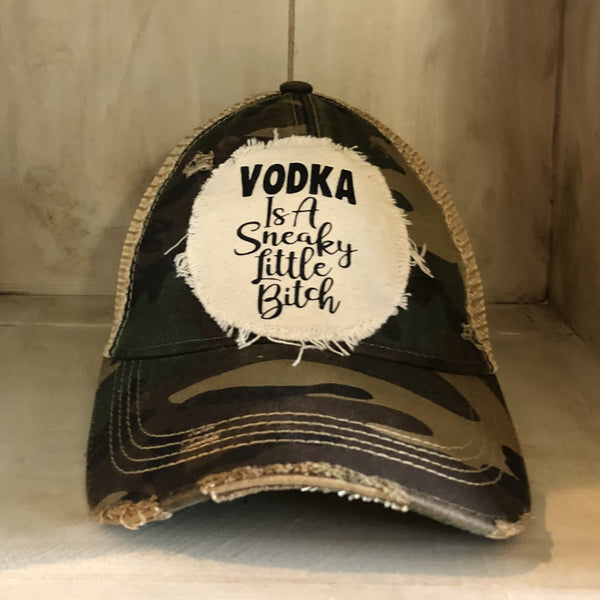 Vodka Is a Sneaky Little Bitch hat by BohoGroove with black lettering on a distressed off-white patch on a camo vintage distressed snapback.