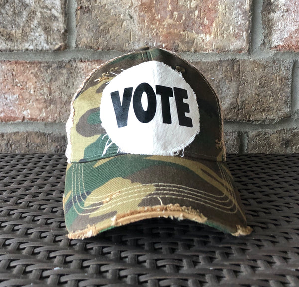 Vote hat by BohoGroove with bold black VOTE lettering on distressed off-white patch and Camo vintage distressed snapback