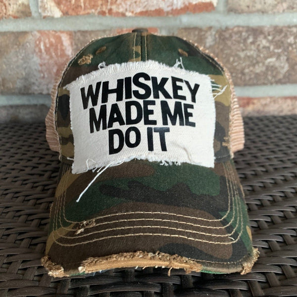 Whiskey Made Me Do It hat by BohoGroove with black Whiskey Made Me Do It lettering on a distressed off-white patch on a camo vintage distressed snapback trucker hat.