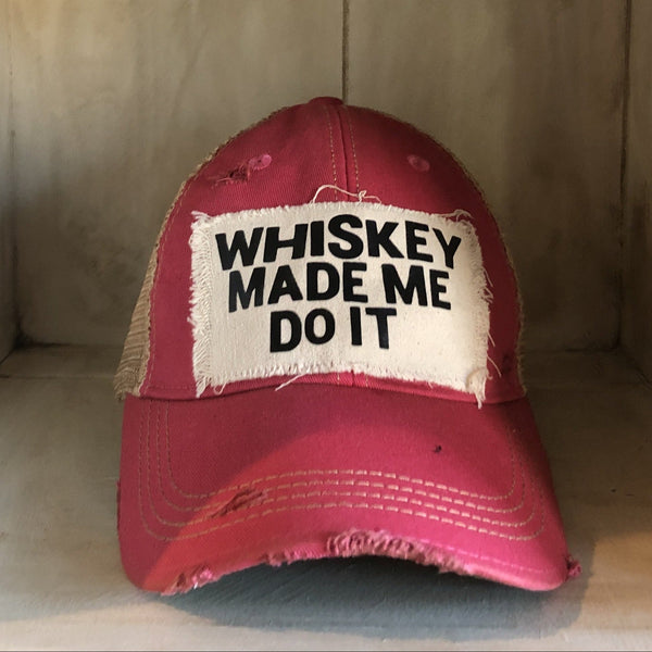 Whiskey Made Me Do It hat by BohoGroove with black Whiskey Made Me Do It lettering on a distressed off-white patch on a pink vintage distressed snapback trucker hat.