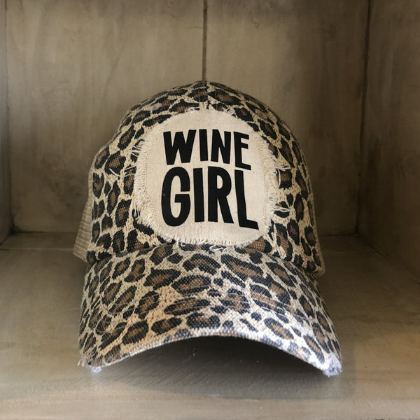 Wine Girl hat by BohoGroove with black Wine Girl lettering and wine glass graphic on a distressed off-white patch on a leopard vintage distressed snapback trucker hat.