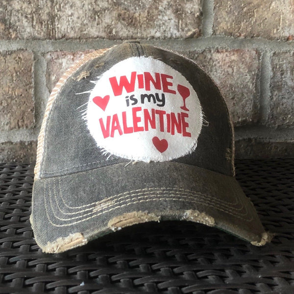 Wine is My Valentine hat by BohoGroove with red Wine is My Valentine lettering, heart graphics, and wine glass graphic on a distressed off-white patch on a black vintage distressed snapback trucker hat.